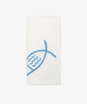 The Pezza Napkin, Set of 6, features white linen napkins each with a simple blue fish design hand block-printed on one side, showcased neatly folded against a plain background.