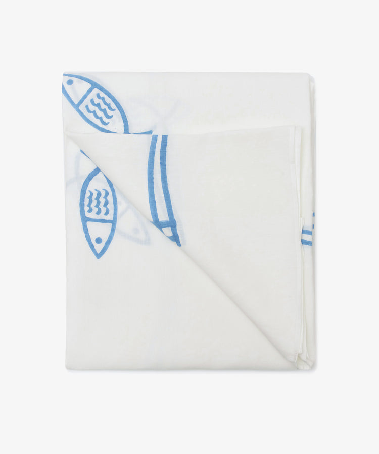The Pezza Tablecloth, a folded white linen with a blue fish motif hand block-printed along the edge, is partially visible against a plain white background.