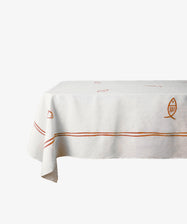 The Pezza Tablecloth is a rectangular white linen tablecloth featuring red and orange stripes with small fish designs, ideal for bringing a coastal touch to your table dÃ©cor.