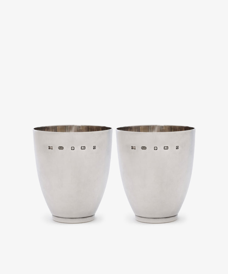 A Vintage Pair of Silver Beakers, hallmarked Sheffield 2004, polished to a bright finish, are displayed side by side on a white background—elegant contemporary camp cups with timeless appeal.