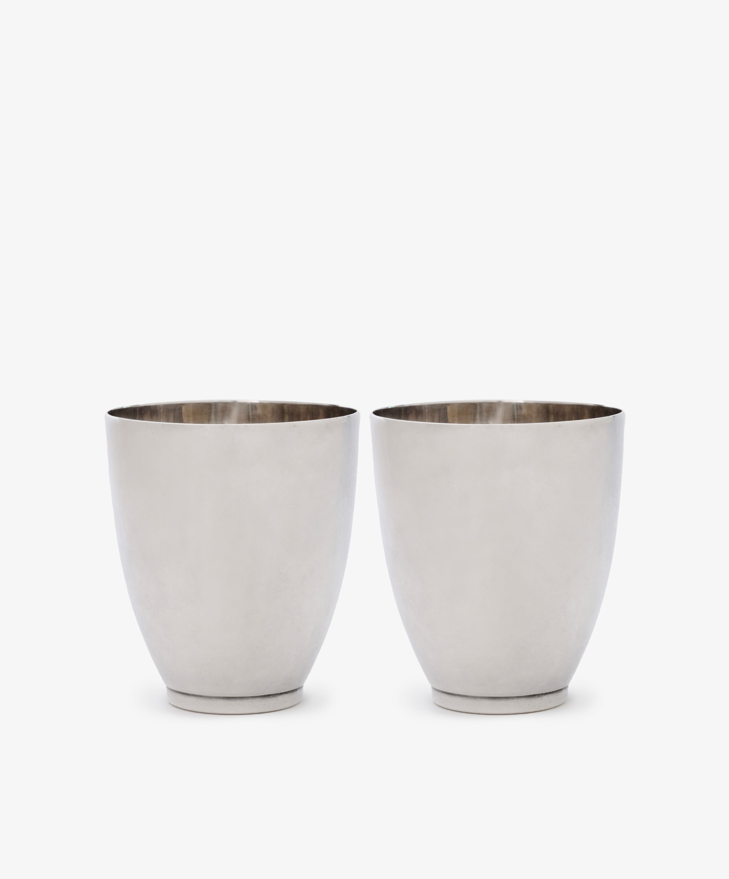 A Vintage Pair of Silver Beakers is displayed side by side on a white background, their minimalist design evoking the timeless elegance of Sheffield 2004.