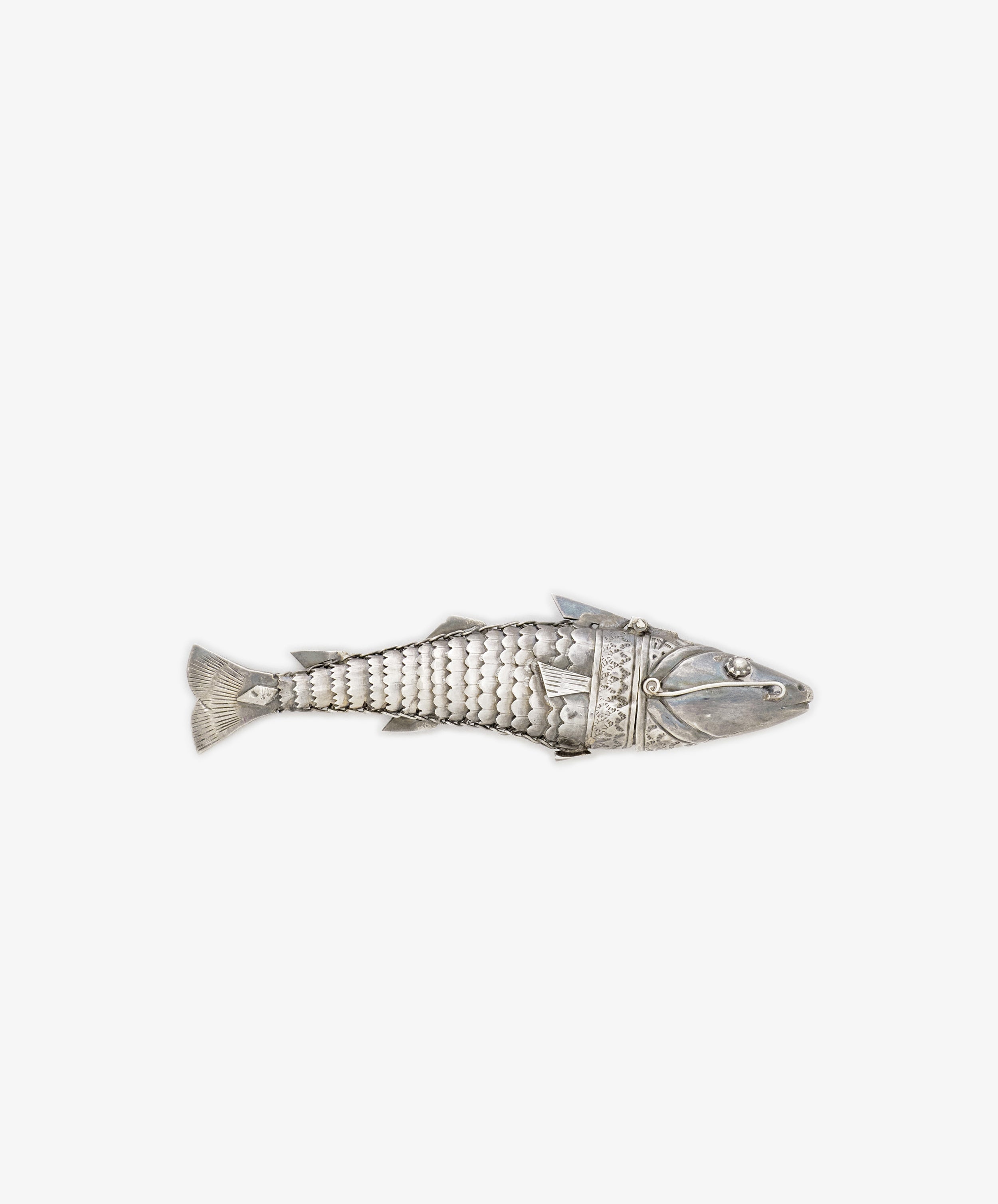 The Vintage Silver Articulating Fish features a segmented, fish-shaped body with detailed fins and is photographed on a white background—a unique talisman believed to bring luck.