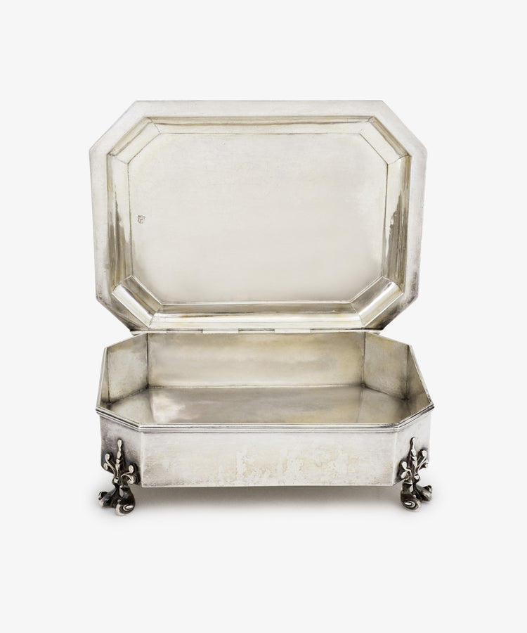 The Vintage English Silver Casket features a rectangular shape, hinged lid, and four decorative feet, reminiscent of Charles II period dressing table boxes, displayed against a plain white background.