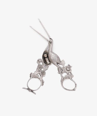 Vintage Dutch Silver Ribbon Nips, shaped like a stork with floral accents around the finger holes, evoke the charm of antique sewing tools and are styled after traditional Dutch silver designs. Shown against a white background.