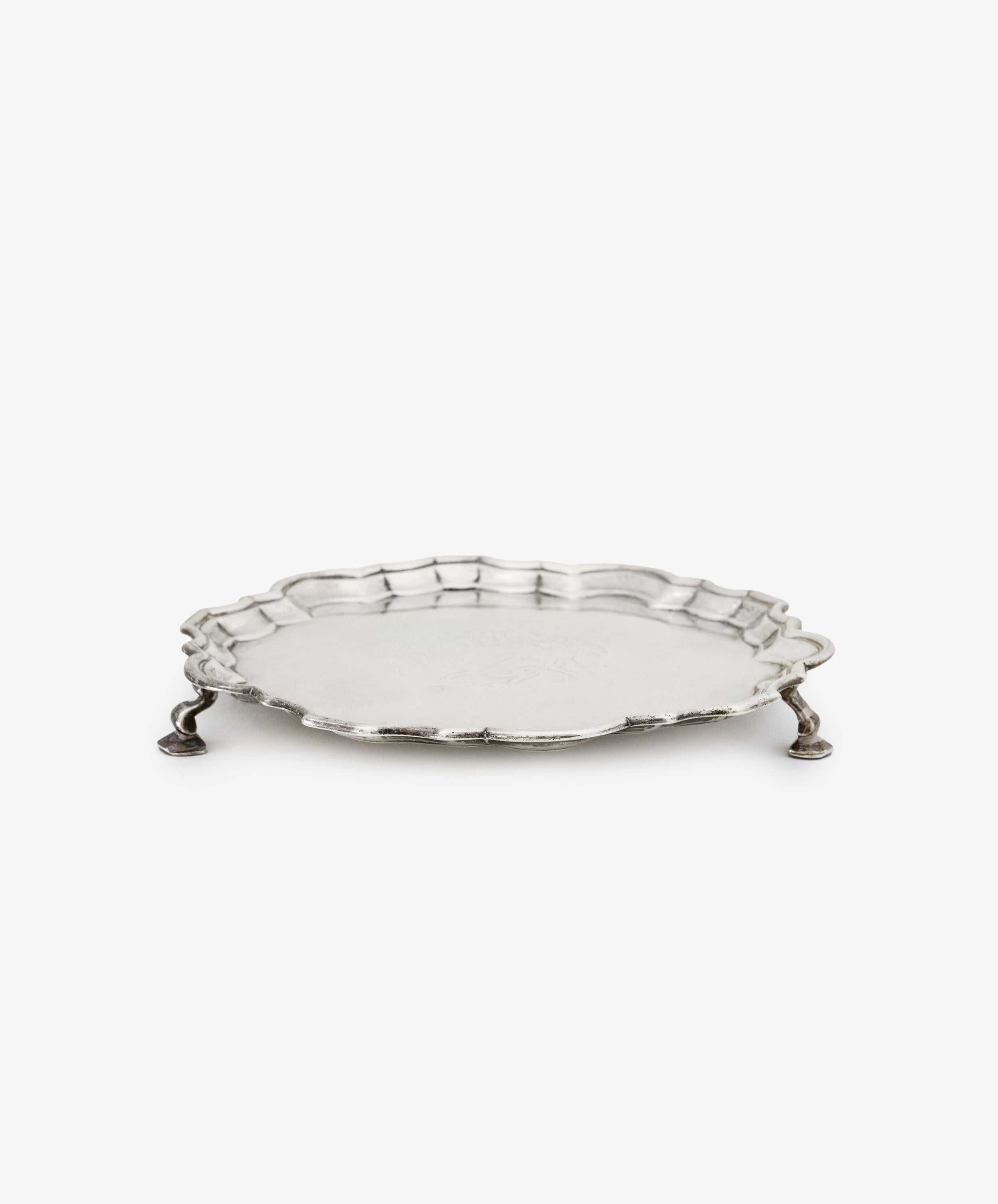 A Vintage English Salver with a round scalloped edge and three ornate legs, crafted in silver by Thomas Farren in the 18th century, displayed on a plain white background.