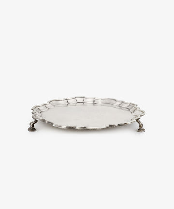 A Vintage English Salver with a round scalloped edge and three ornate legs, crafted in silver by Thomas Farren in the 18th century, displayed on a plain white background.