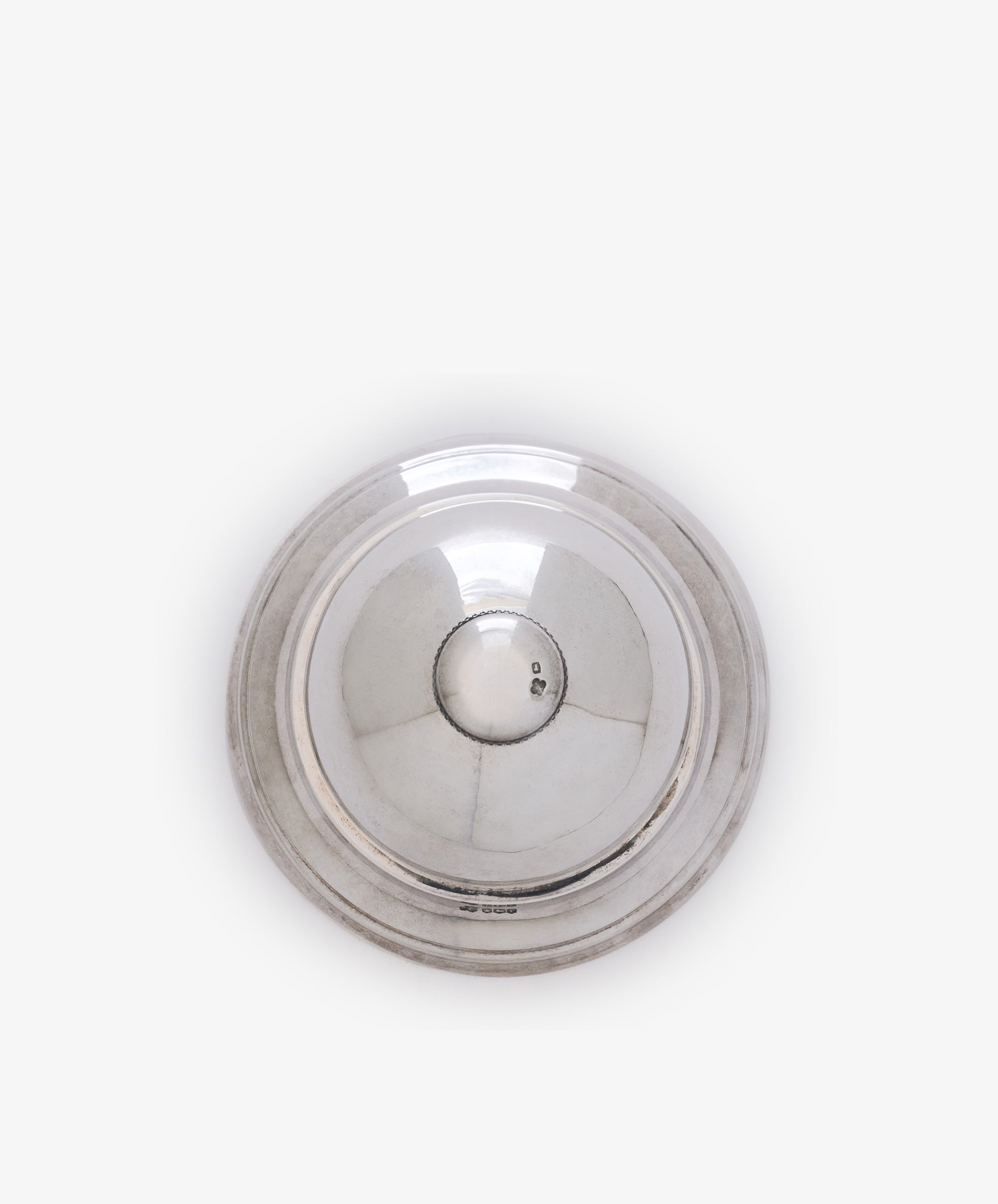 A vintage English silver table bell with a round, reflective surface and slightly raised rim, seen from above against a plain white background.