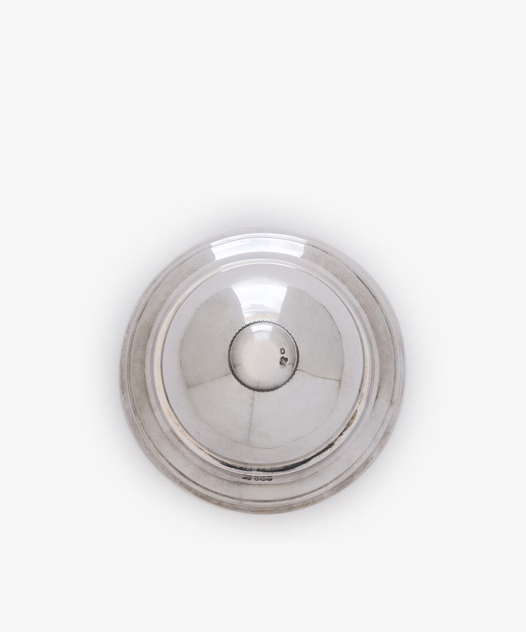 A vintage English silver table bell with a round, reflective surface and slightly raised rim, seen from above against a plain white background.