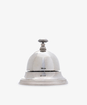 The Vintage English Silver Table Bell features a round dome and a knob on top, set on a flat base, ideal as a dinner bell or elegant household accessory. Presented against a plain white background.