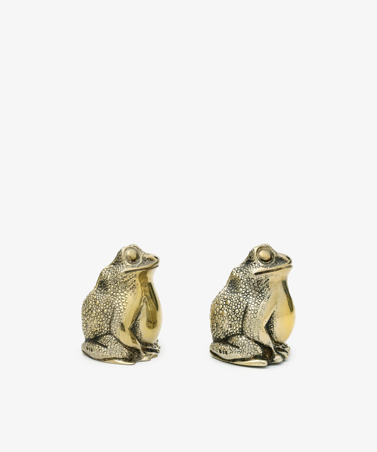 A vintage pair of Tiffany frog salt and pepper shakers, crafted in metallic silver with textured surfaces, are displayed side by side against a plain white background.