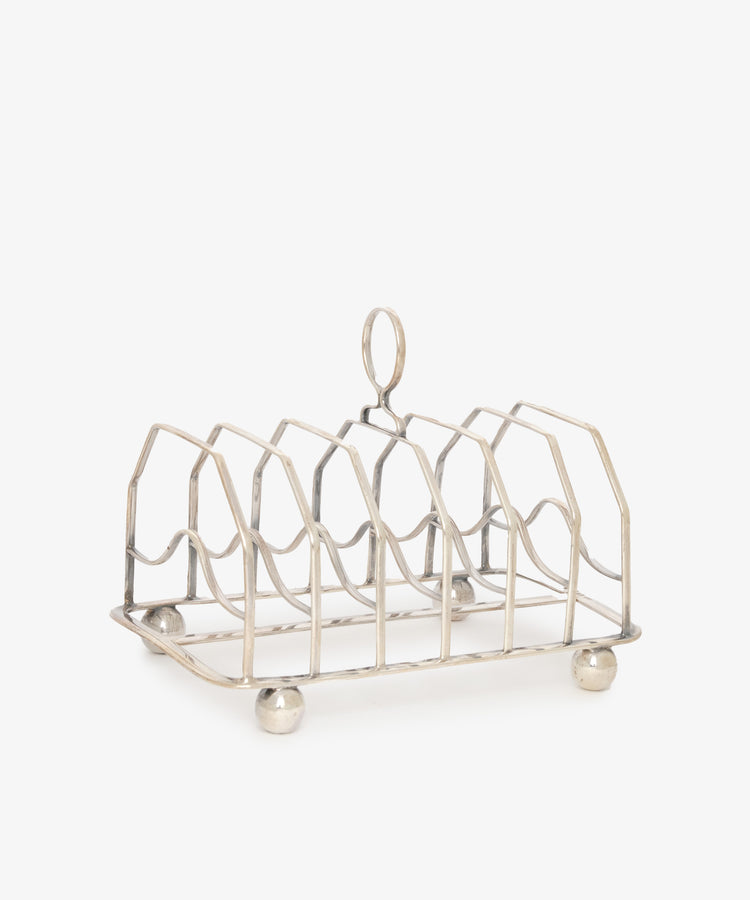 The Vintage George III Toast Rack, crafted from English silver with four slots, a central handle, and four round feet, is set against a plain white background—an ideal piece for any vintage collection.
