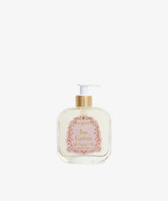 A clear rectangular pump bottle with a gold and white dispenser, labeled Rosa Gardenia Bath Gel, containing floral bath gel, is set against a plain white background.