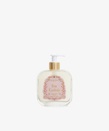 A clear rectangular pump bottle with a gold and white dispenser, labeled Rosa Gardenia Bath Gel, containing floral bath gel, is set against a plain white background.