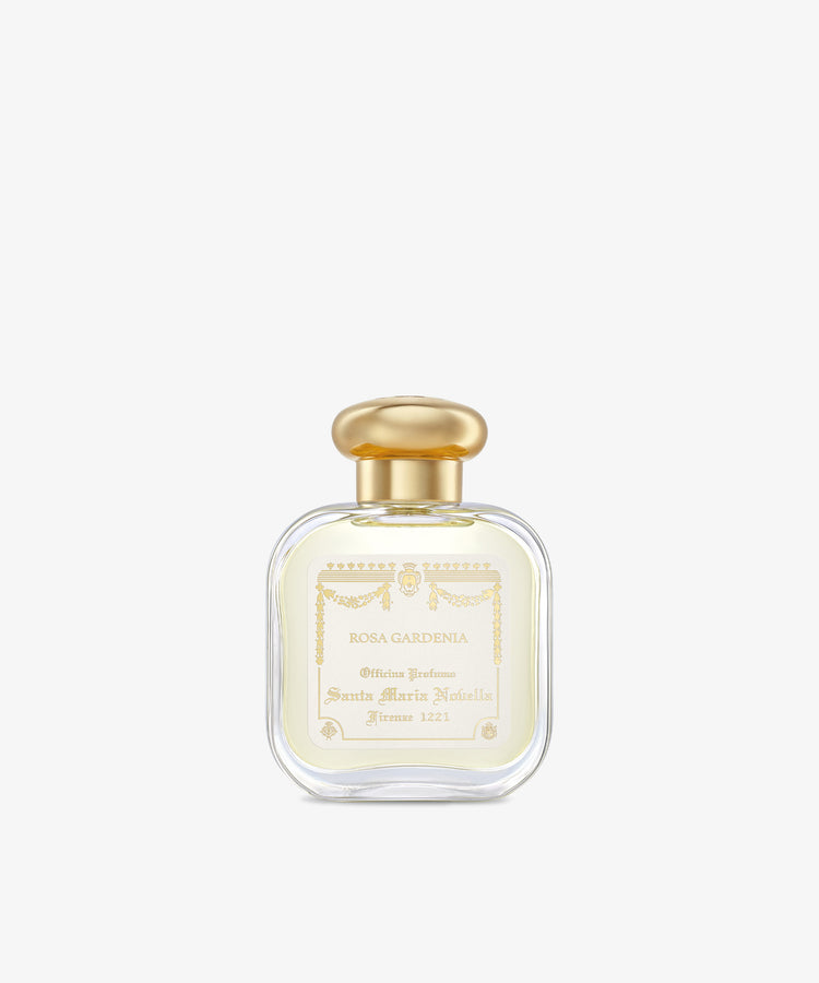 A clear glass bottle of Rosa Gardenia Eau de cologne, featuring a gold cap and white and gold label, is elegantly centered on a plain white background.