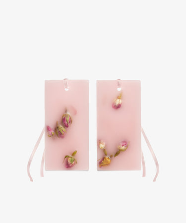 Set of 2 Rosa Gardenia Scented Wax Tablets—rectangular pink wax with dried rosebuds, each featuring a hole and pink ribbon for hanging—are shown against a white background and release a charming Tuscan Hills-inspired aroma.