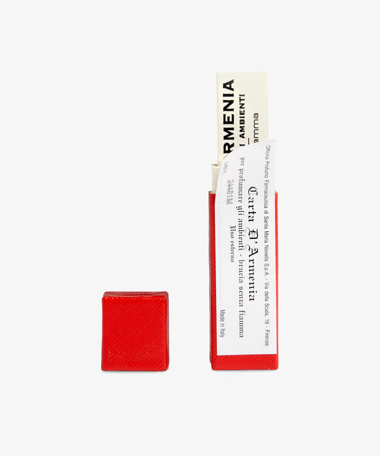 A small red Armenia Paper box with white aromatic papers partially pulled out sits alongside its closed lid on a white background, releasing a subtle resinous scent.