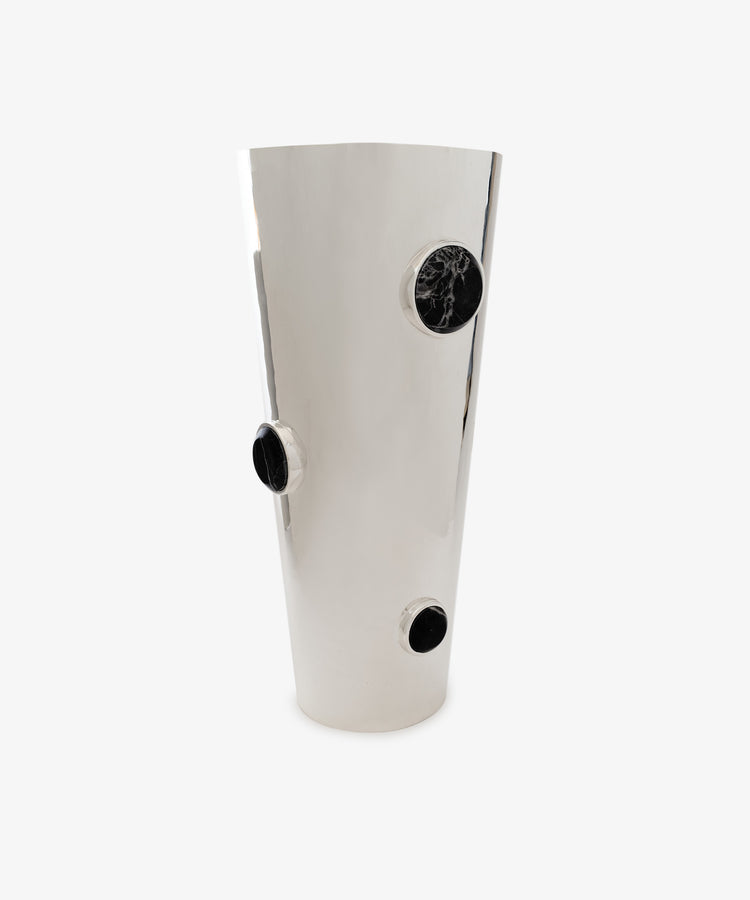 Paros Cone Vase: A tall, shiny steel vessel featuring three round black marble accents arranged at different heights along its sleek surface, set against a plain white background. The Paros Cone Vase seamlessly blends modern elegance with bold contrast, making a dramatic decorative statement.