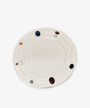 The Verola Round Tray is a white, circular tray adorned with evenly spaced colored stones embedded along its rim, evoking the look of an elegant colored stone ring, and is shown against a plain white background.