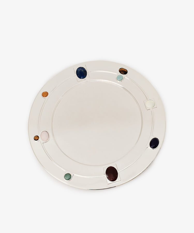 The Verola Round Tray is a white, circular tray adorned with evenly spaced colored stones embedded along its rim, evoking the look of an elegant colored stone ring, and is shown against a plain white background.