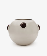 The Paros Round Vase is a white, round ceramic vase featuring three evenly spaced circular dark brown accents around its curved surface, reminiscent of Paros stone. It is displayed against a plain white background.