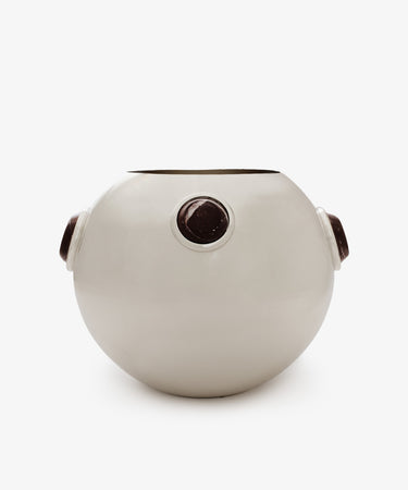 The Paros Round Vase is a white, round ceramic vase featuring three evenly spaced circular dark brown accents around its curved surface, reminiscent of Paros stone. It is displayed against a plain white background.