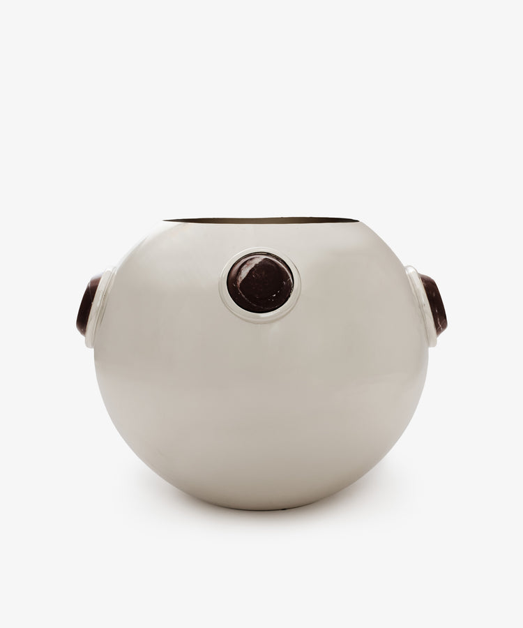 The Paros Round Vase is a white, round ceramic vase featuring three evenly spaced circular dark brown accents around its curved surface, reminiscent of Paros stone. It is displayed against a plain white background.