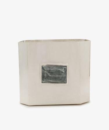 The Paros Square Vase, a rectangular silver-colored metal container reminiscent of a Brancusi vase, features a raised, textured rectangular detail in the center on one side and is set against a white background.