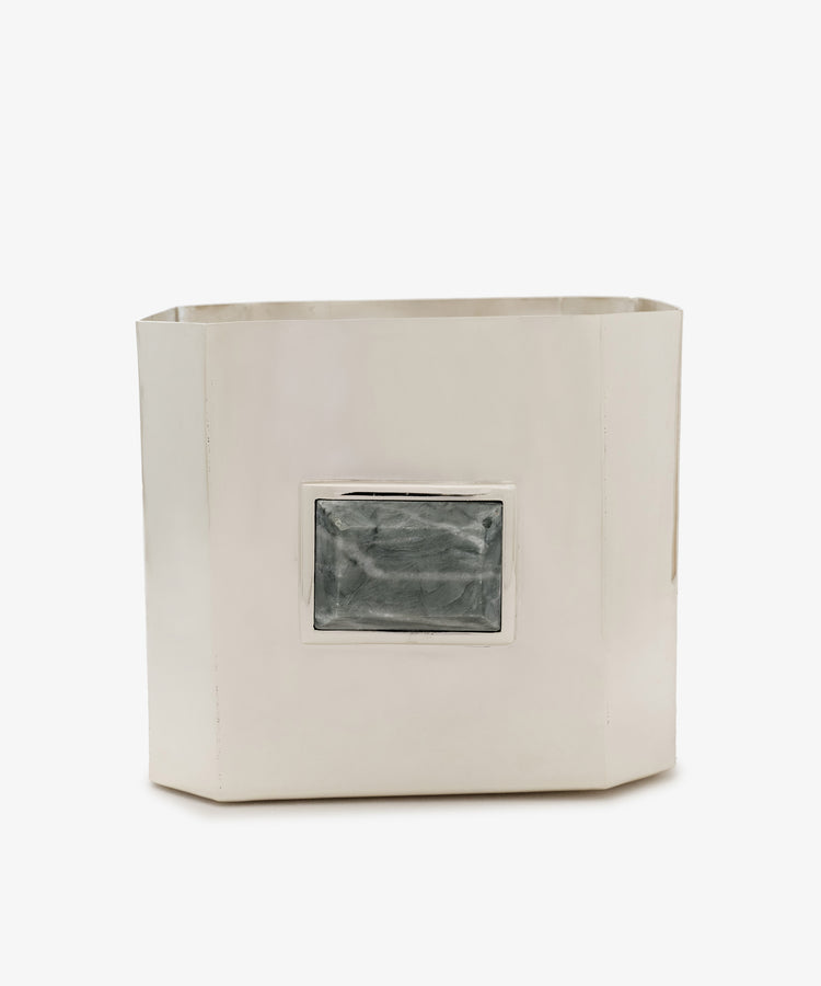 The Paros Square Vase, a rectangular silver-colored metal container reminiscent of a Brancusi vase, features a raised, textured rectangular detail in the center on one side and is set against a white background.