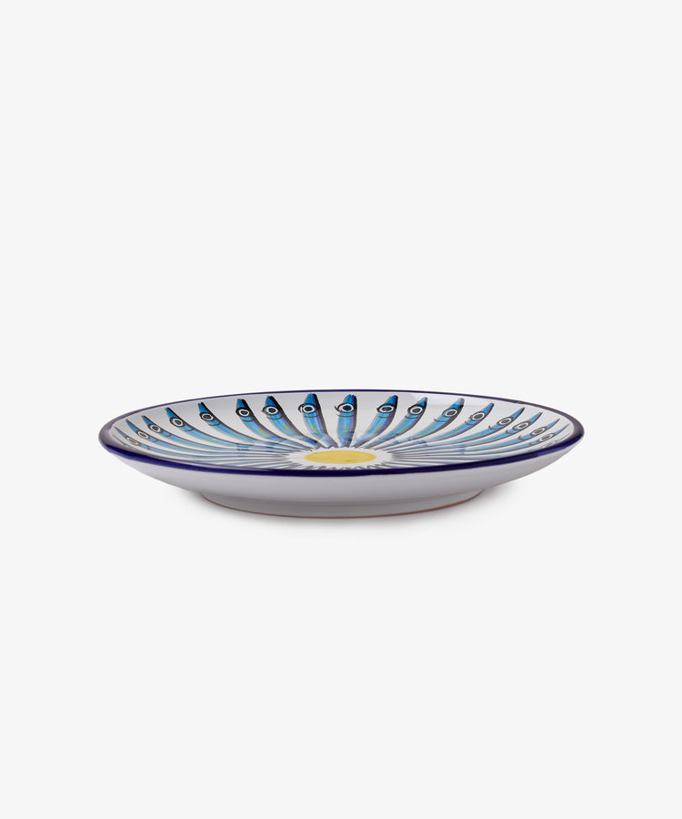 The Tommaso Platter is a round ceramic plate with a white base, featuring a blue and green peacock feather pattern radiating from the center, capturing the vibrant artistry of the Amalfi Coast.