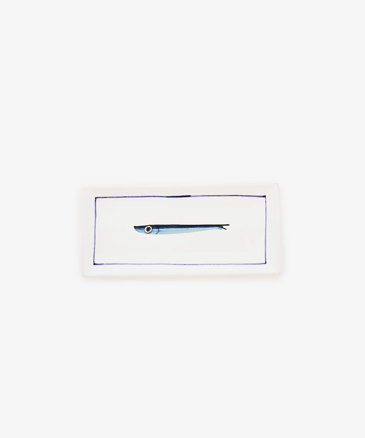The Tommaso Rectangle Tray is a white ceramic serving tray featuring a simple illustration of a small cobalt blue fish in the center, framed by a thin blue border.
