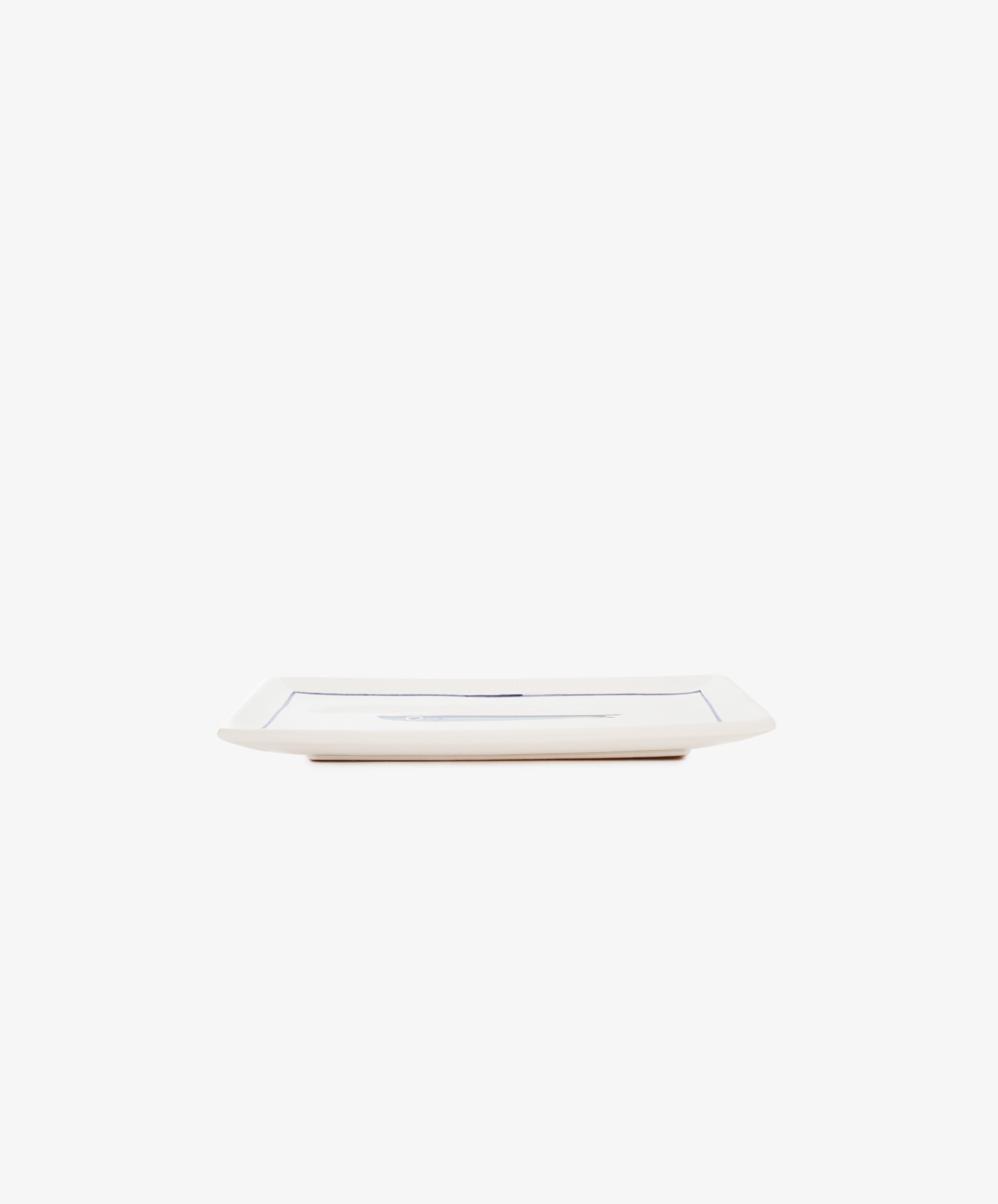 The Tommaso Rectangle Tray is a rectangular white ceramic serving tray with slightly raised edges, hand-painted with delicate cobalt blue fish, shown from the side against a plain white background.