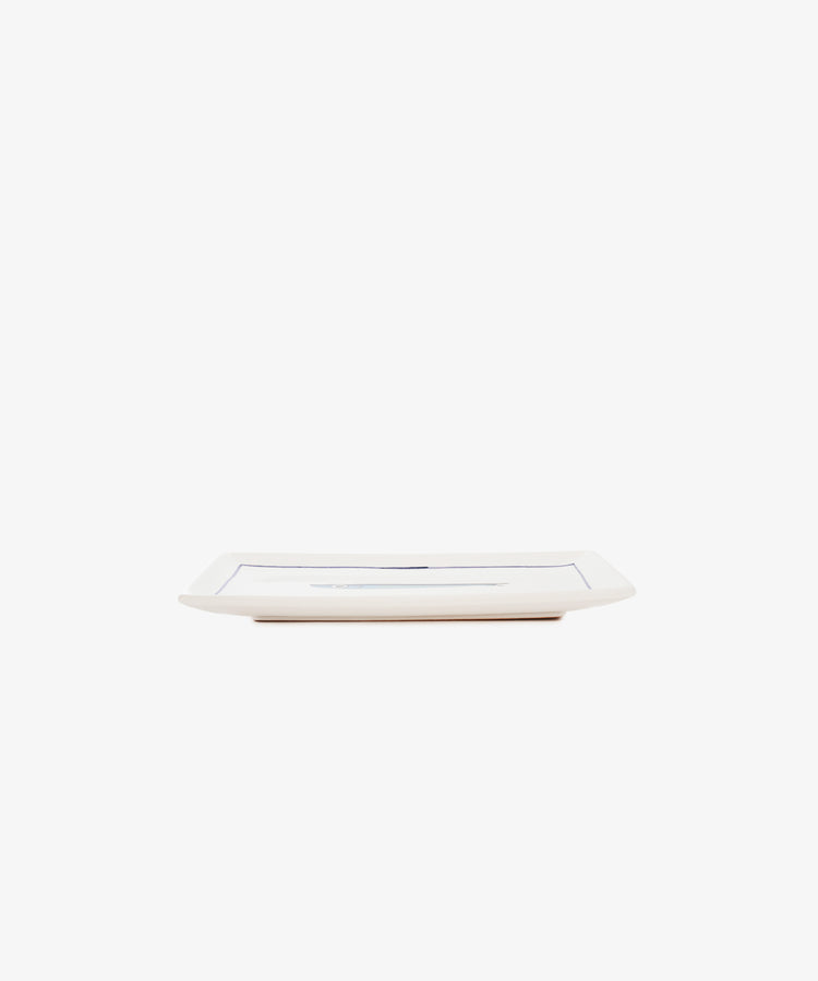 The Tommaso Rectangle Tray is a rectangular white ceramic serving tray with slightly raised edges, hand-painted with delicate cobalt blue fish, shown from the side against a plain white background.