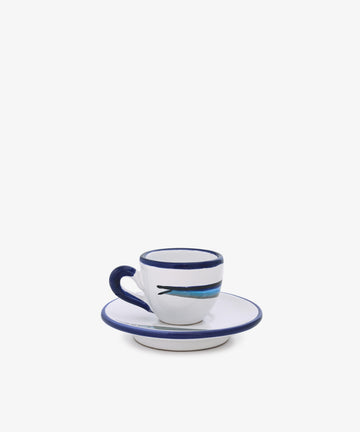 The Tommaso Espresso Set, a white ceramic set with blue rim, handle, and Mediterranean-inspired fish design, sits on its matching saucer against a plain white background.