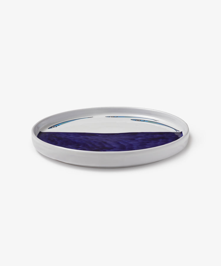 A round white ceramic Tommaso Flying Fish Platter featuring a glossy blue and purple abstract design inspired by the Amalfi Coast, shown on a white background.