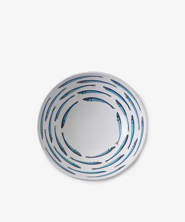 A round white Tommaso Salad Bowl features blue sardines swimming in concentric circles, evoking the charm of serving pieces from the Amalfi Coast.