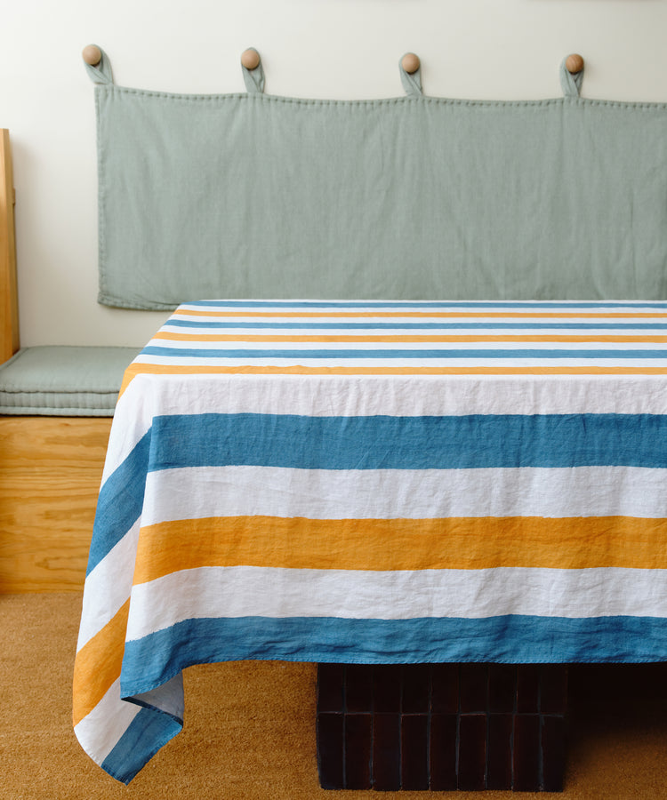 Striped Tablecloth by Summerill & Bishop. White linen cloth in blue and orange stripes draped over table in studio.