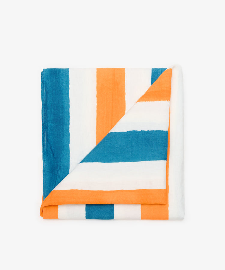 Striped Tablecloth by Summerill & Bishop. Folded white linen cloth in blue and orange stripes, with corner flipped down.