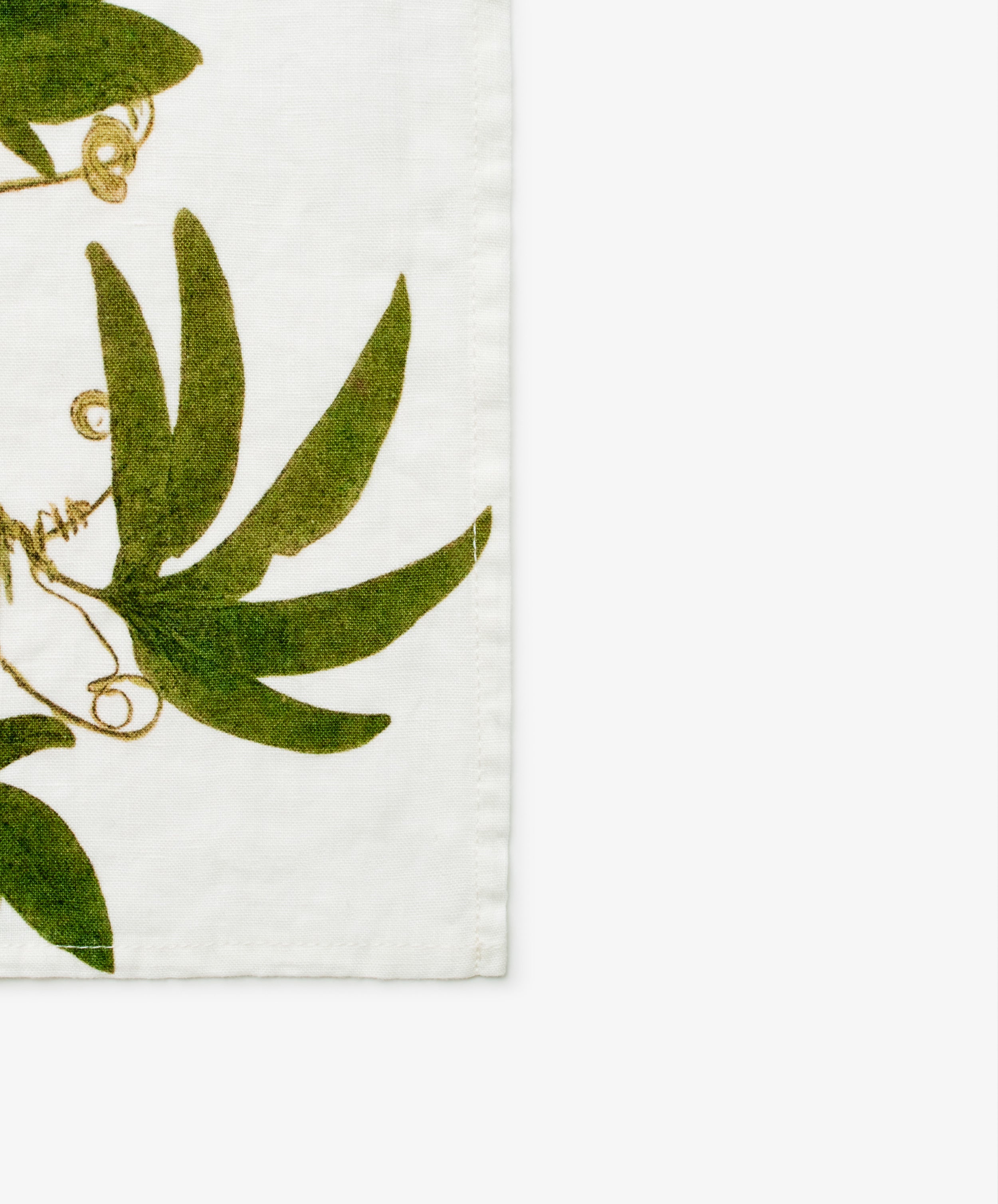 Tisane Herb Napkin. Green vine pattern on white linen. Close up of corner.