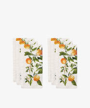 Six L’Orangerie Napkins, a set of six white linen napkins by Le Jacquard Français featuring an orange fruit and blossom print inspired by classical French gardens, arranged in two neat stacks against a plain background.