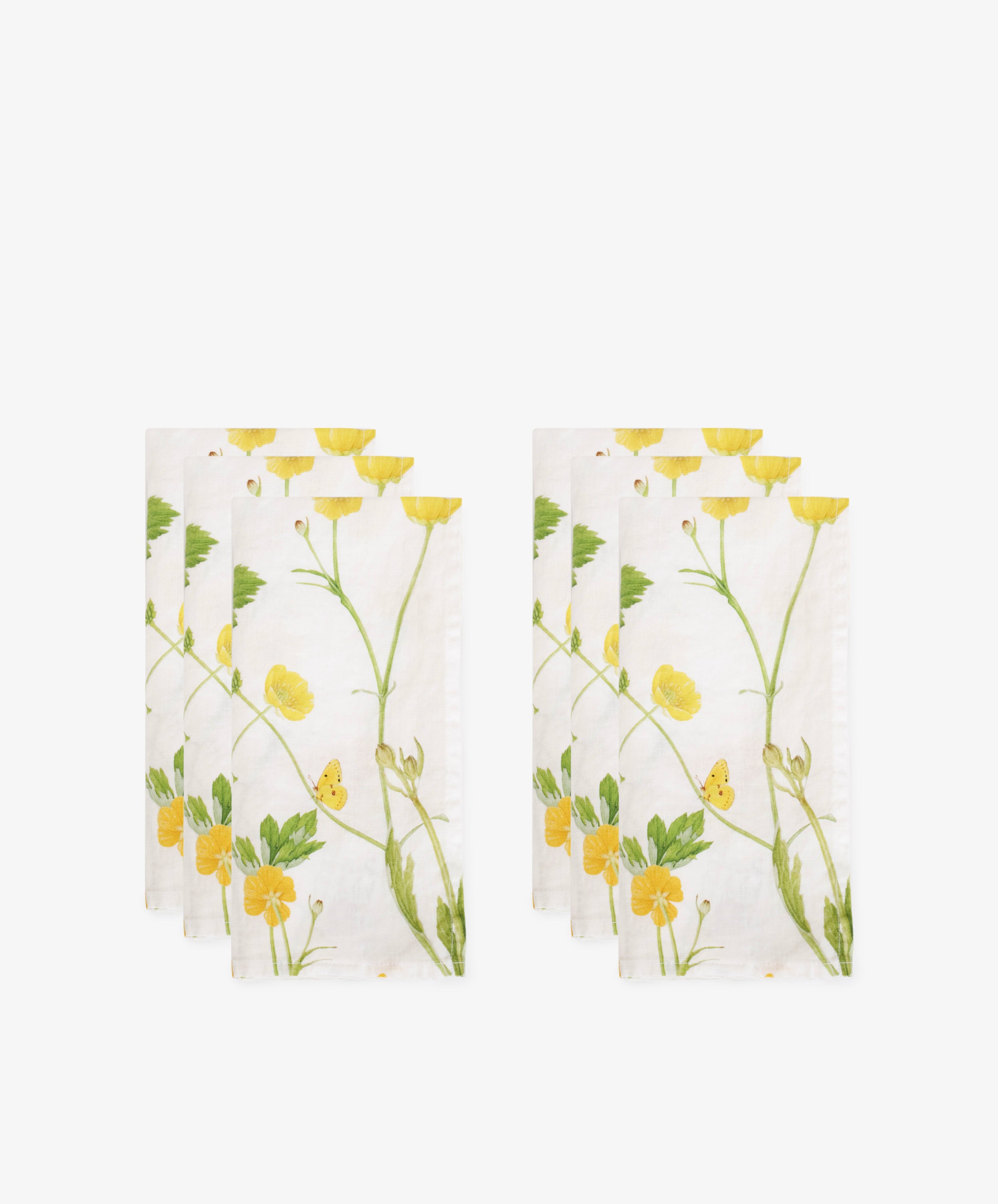 The Buttercup Linen Napkin, Set of 6, features white linen with a yellow and green floral print. Neatly arranged against a white background, these napkins add elegance and brighten any table setting.