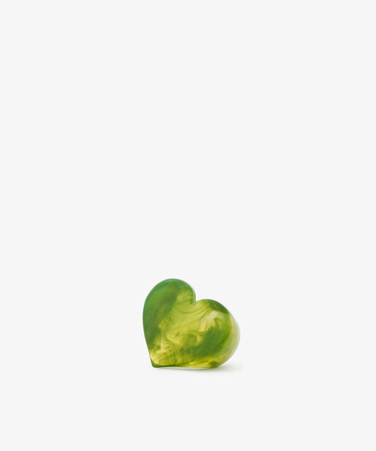 A Heart Resin Napkin Ring, featuring a small, green, heart-shaped design with a marbled pattern and sculptural form, is centered near the bottom of a plain white background.
