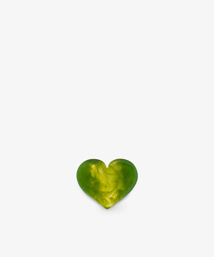 A small, green and yellow marbled heart-shaped object, reminiscent of a sculptural form, is centered at the bottom of a plain white background.