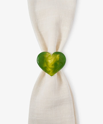 A sculptural Heart Resin Napkin Ring in green, symbolizing love, holds a white cloth napkin against a plain white background.