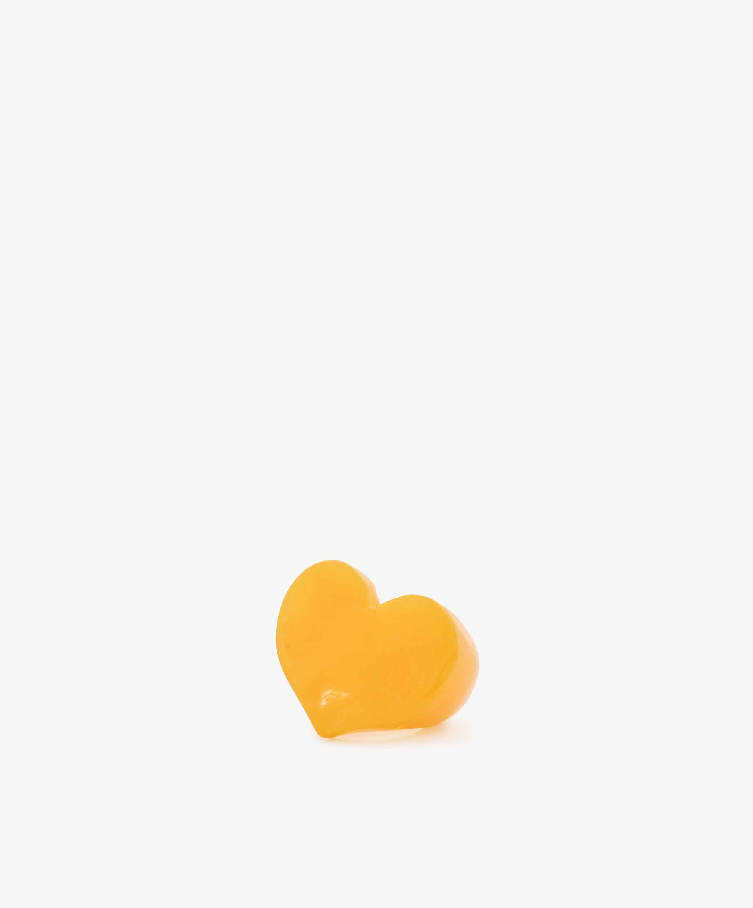 A single Heart Resin Napkin Ring in yellow, sculptural and heart-shaped, is centered against a plain white background with ample empty space above.