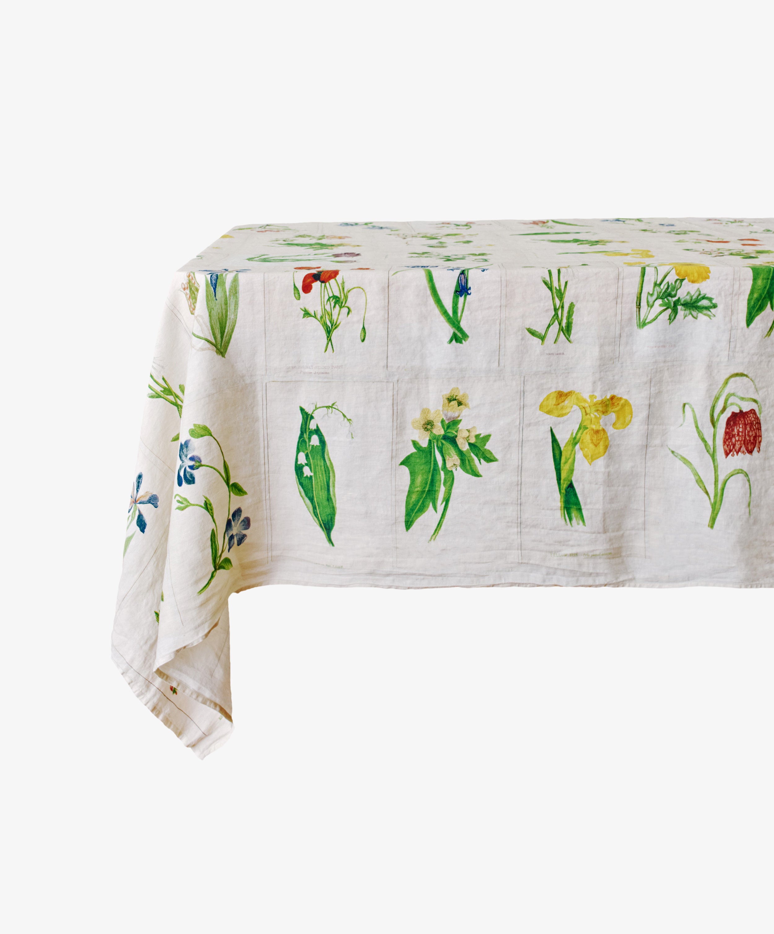 A rectangular table covered with the John Derian Botanical Tiles Tablecloth, featuring a vibrant botanical design with colorful floral and leaf illustrations.