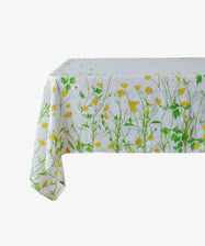 A rectangular garden table looks elegant with the Buttercup Linen Tablecloth, featuring a white base decorated with green and yellow floral patterns.