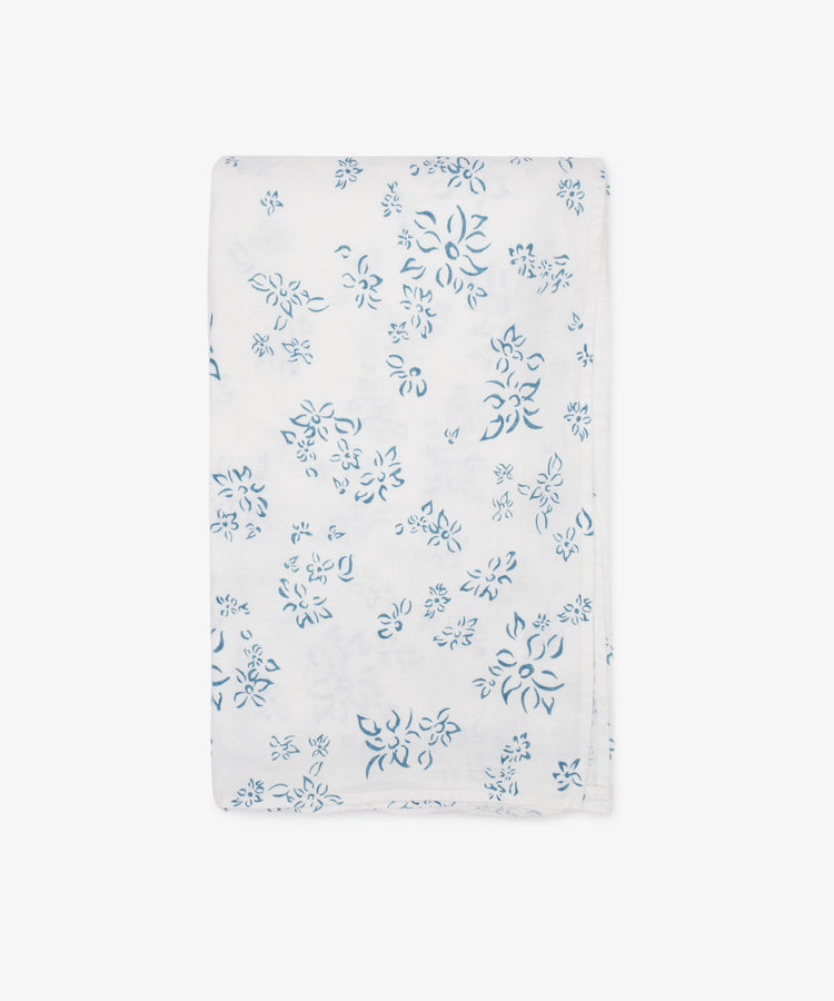 The Falling Flower Linen Tablecloth from Summerill & Bishop, featuring a white base with a blue hand-drawn flower pattern, is shown folded against a plain white background.