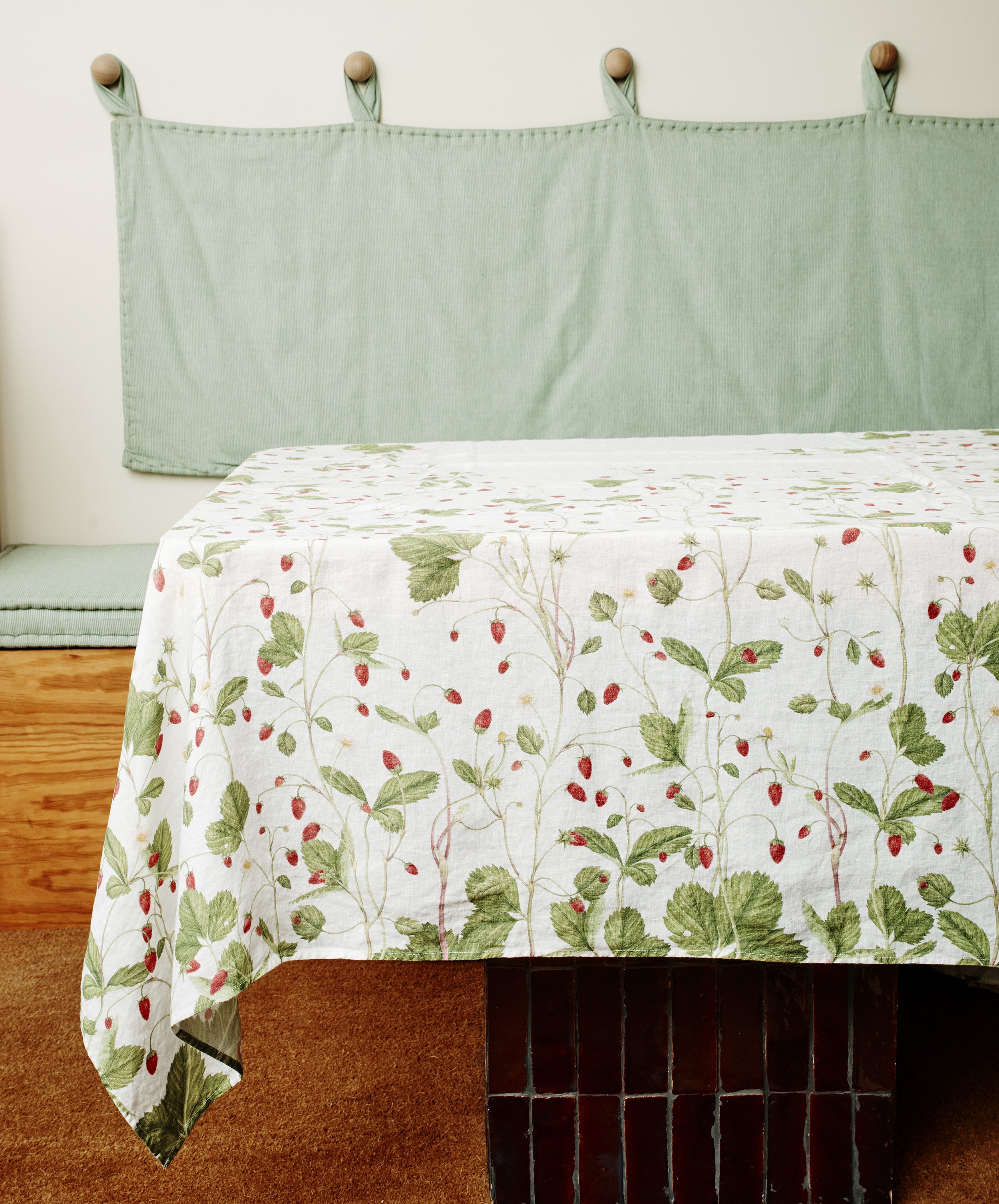 Fraise de Bois tablecloth. Image of tablecloth draped over dining table. Side view.