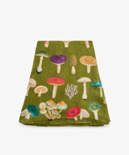 The John Derian Fungi Round Tablecloth showcases an array of vibrant mushroom illustrations on green cloth, reminiscent of botanical prints, and is displayed folded against a white background. Ideal as a statement piece for your table or as a distinctive addition to curiosity cabinet décor.