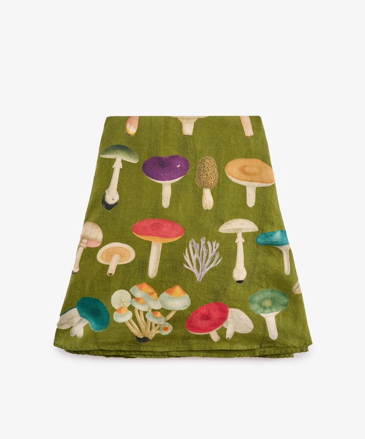 The John Derian Fungi Round Tablecloth showcases an array of vibrant mushroom illustrations on green cloth, reminiscent of botanical prints, and is displayed folded against a white background. Ideal as a statement piece for your table or as a distinctive addition to curiosity cabinet décor.